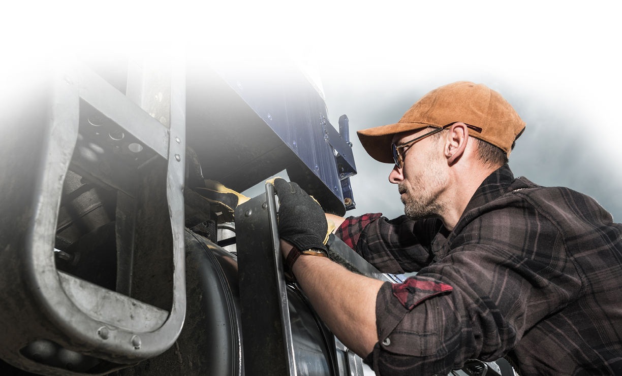 Semi Truck Driver in His 40s Checking Vehicle Elements Near Fuel Tank. Heavy Duty Transportation Theme.